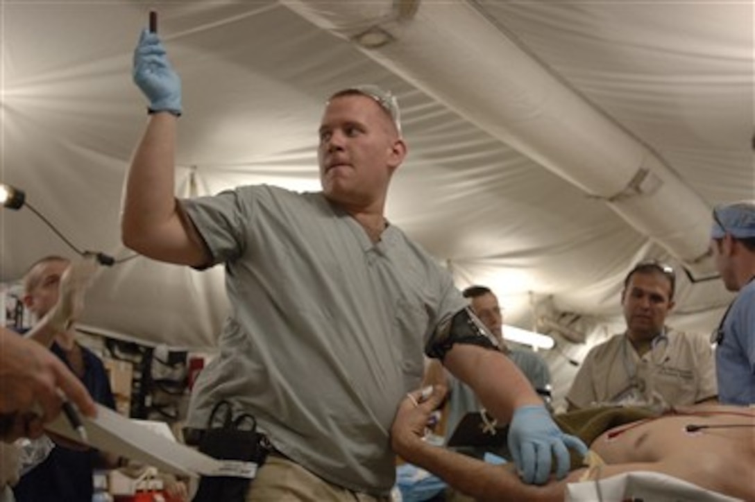 Air Force Staff Sgt. Donovan O'Linc passes a vial of drawn blood to a nurse during medical operations at the Air Force theater hospital on Balad Air Base, Iraq, on Feb. 19, 2007.  O'Linc is an aerospace medical technician assigned to the 332nd Expeditionary Medical Group.  