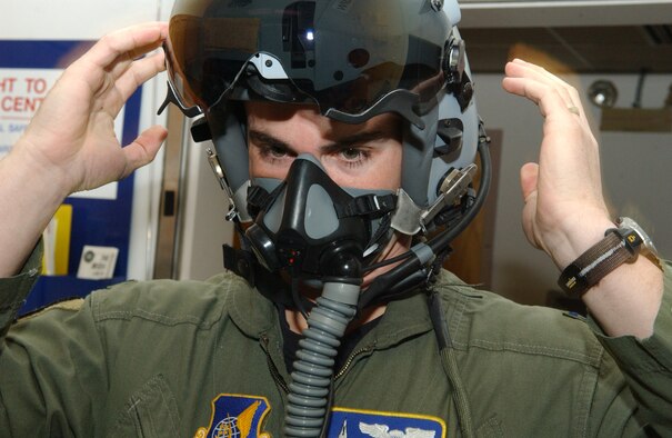 EIELSON AIR FORCE BASE, Alaska -- Captain Jeremey Wimer, 18th Fighter Squadron F-16 pilot, tries on a newly issued flight helmet while gearing up Feb. 21 at the 18th Fighter Squadron. The new helmet mounted queing system has targeting technology that projects holographic data on the inside right of the visor in the form of a container, or que and allows pilots to continually survey and distinguish between friendly and enemy air and ground targets. ( U. S. Air Force phot by Airman 1st Class Christopher Griffin.)
