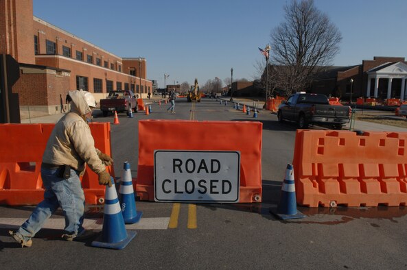 A contractor places road cones in front of the traffic barriers on Brookley Avenue near the base gym Feb. 23. Traffic flow on Brookley Avenue from McChord Street to the north end of Hangar 1 will be interrupted through March 22 for the installation of new underground chilled-water lines. Brookley will be completely closed to traffic for two weeks. Detours will be posted. Access to the fitness center and all facilities along Brookley Avenue will be maintained. For more information, call Curtis Martin at (202) 767-1250. (U.S. Air Force photo by Airman First Class Timothy Chacon)

