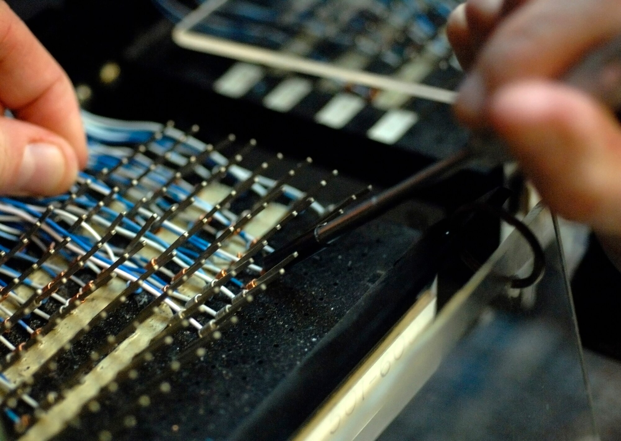 Senior Airman Erin Gilmore, a voice network systems journeyman assigned to the 1st Communications Squadron, uses a wrap tool to terminate a jumper cable telephone wire to an line equipment number Feb. 21. More than 22,000 wires connect the many telephones on Langley. (U.S Air Force Photo/Staff Sgt. Eric T. Sheler)