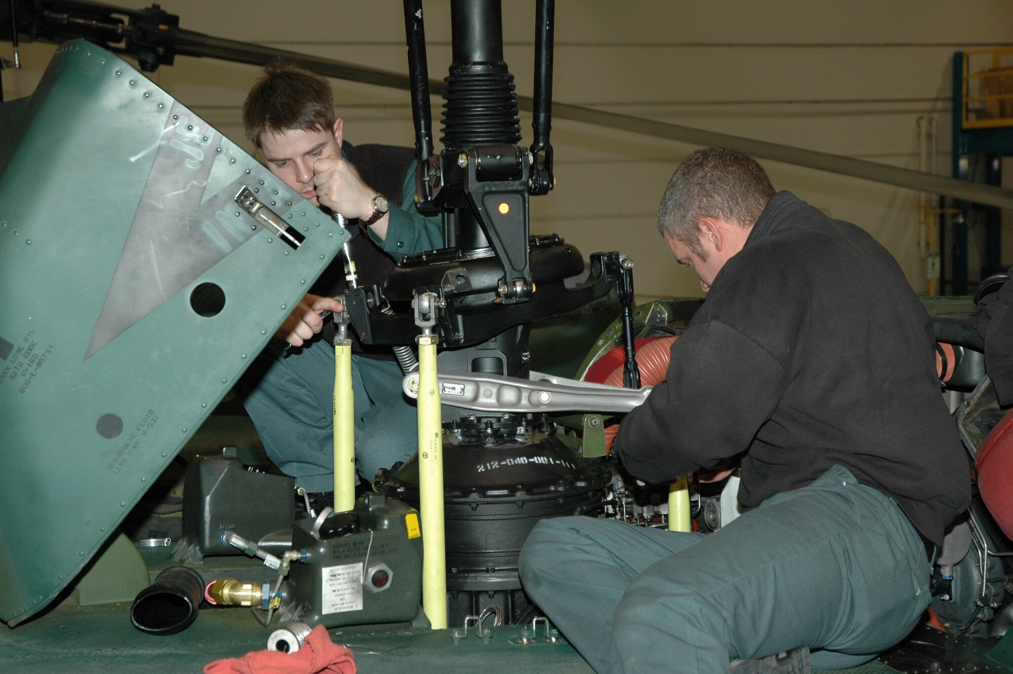 Dallas Robertson (left) and Russ Fry change the cyclic tube on a UH-1N Huey during regular maintenance. Both men are employed by Doss Aviation, the contractor responsible for maintaining the 40th Helicopter Squadron's assets since 1988.