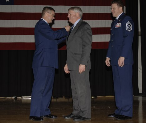 Col. Donald J. Halpin, 22nd Air Refueling Wing commander, inducts Mike Nelson as the 22nd Security Forces honorary commander, while  Chief Master Sgt. Todd Salzman, 22nd ARW command chief, assists during the Annual Honorary Commander's Banquet at McConnell Air Force Base Feb. 22. (Air Force photo by Airman 1st Class Laura Suttles, 22nd Communications Squadron) 