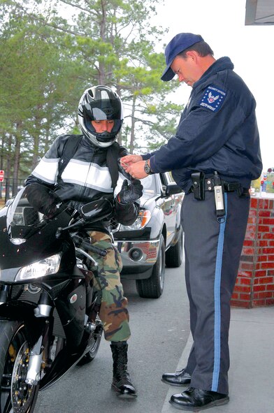 David Taylor, USProtect security officer, inspects an Airman's military identification card at Moody Air Force Base, Ga., Feb. 20.  Effective immediately, vehicles entering Moody will no longer require a windshield decal. Anyone requiring entry will still need to show a valid military ID or visitor pass.  (U.S Air Force photo by Senior Airman Angelita Lawrence)  