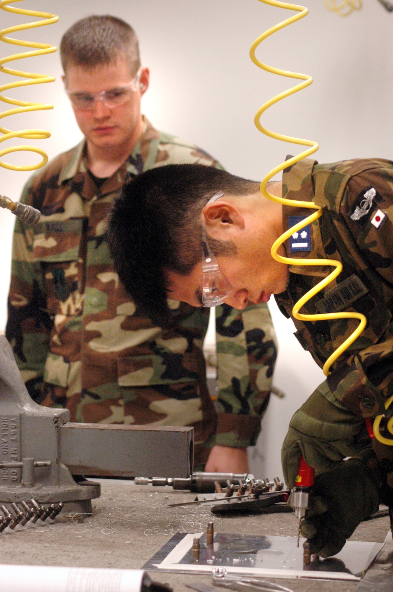 Staff Sgt. Jacob Wall watches as 1st Lt. Yusuke Asano makes a repair.