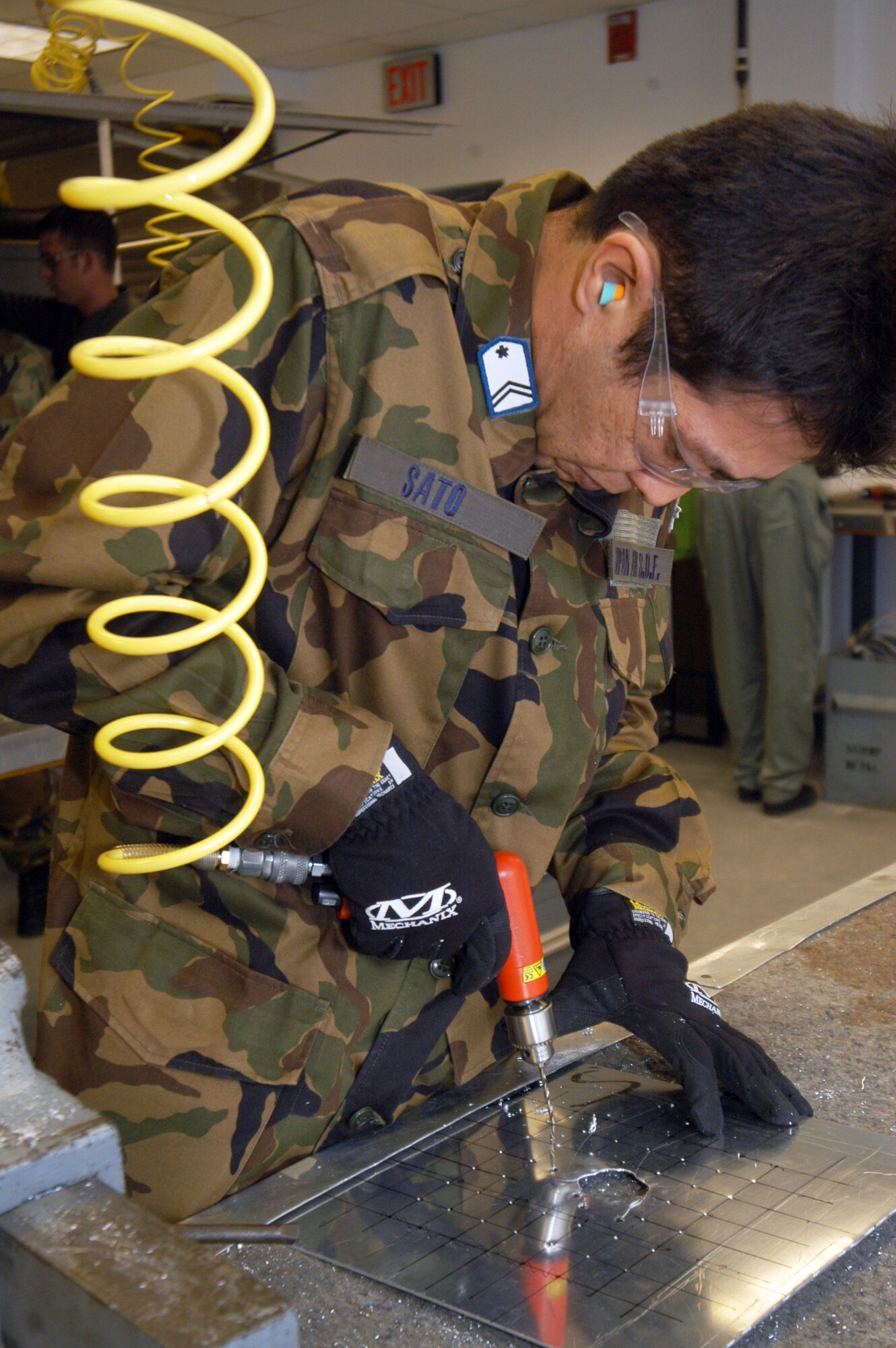 Tech. Sgt. Tatsuya Sato drills rivet holes in a simulated battle damaged piece of sheet metal so a patch can be attached. U.S. Air Force photos by Sue Sapp.