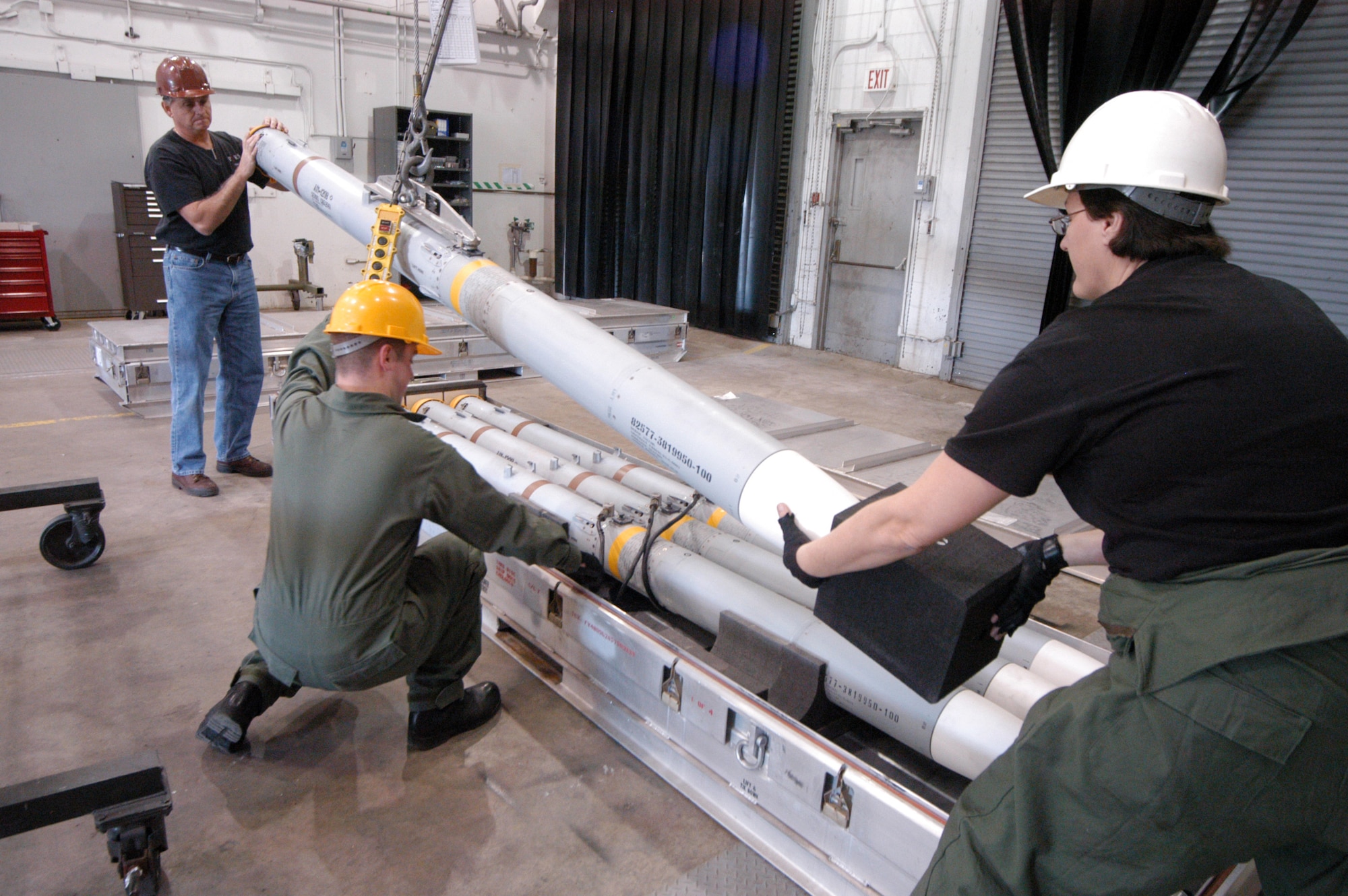 Joe Harbin, Staff Sgt. Christopher Williams and Master Sgt. Patricia Logue load an AIM-120B onto a missile stand. U.S. Air Force photo by Sue Sapp 
