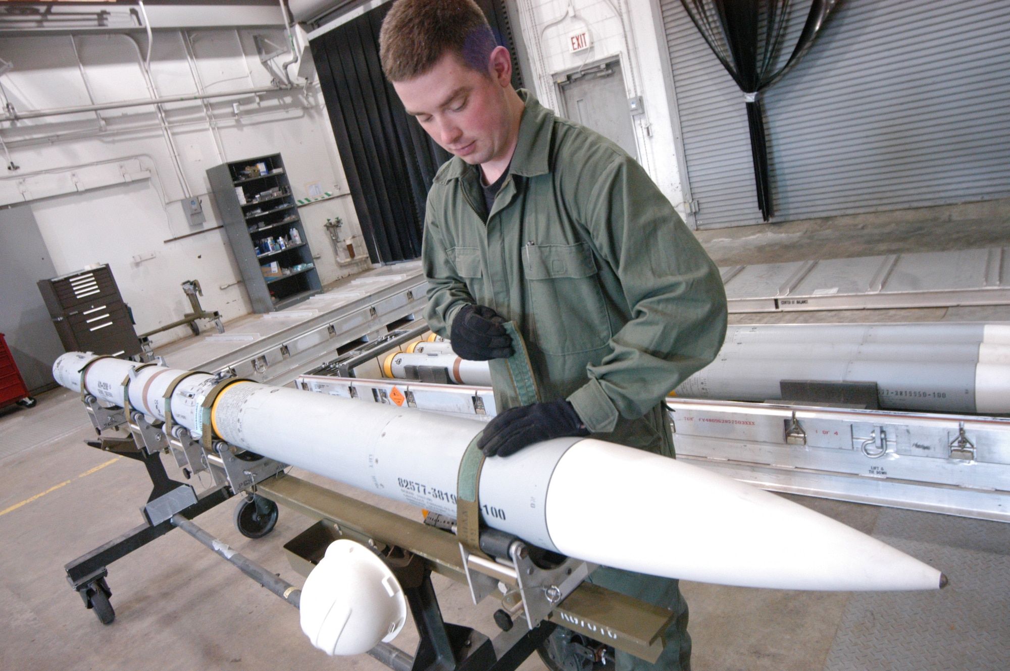 Staff Sgt. Christopher Williams straps an AIM-120B in place. A total of 690 of the missiles will undergo a rocket motor transfer here. U.S. Air Force photos by Sue Sapp