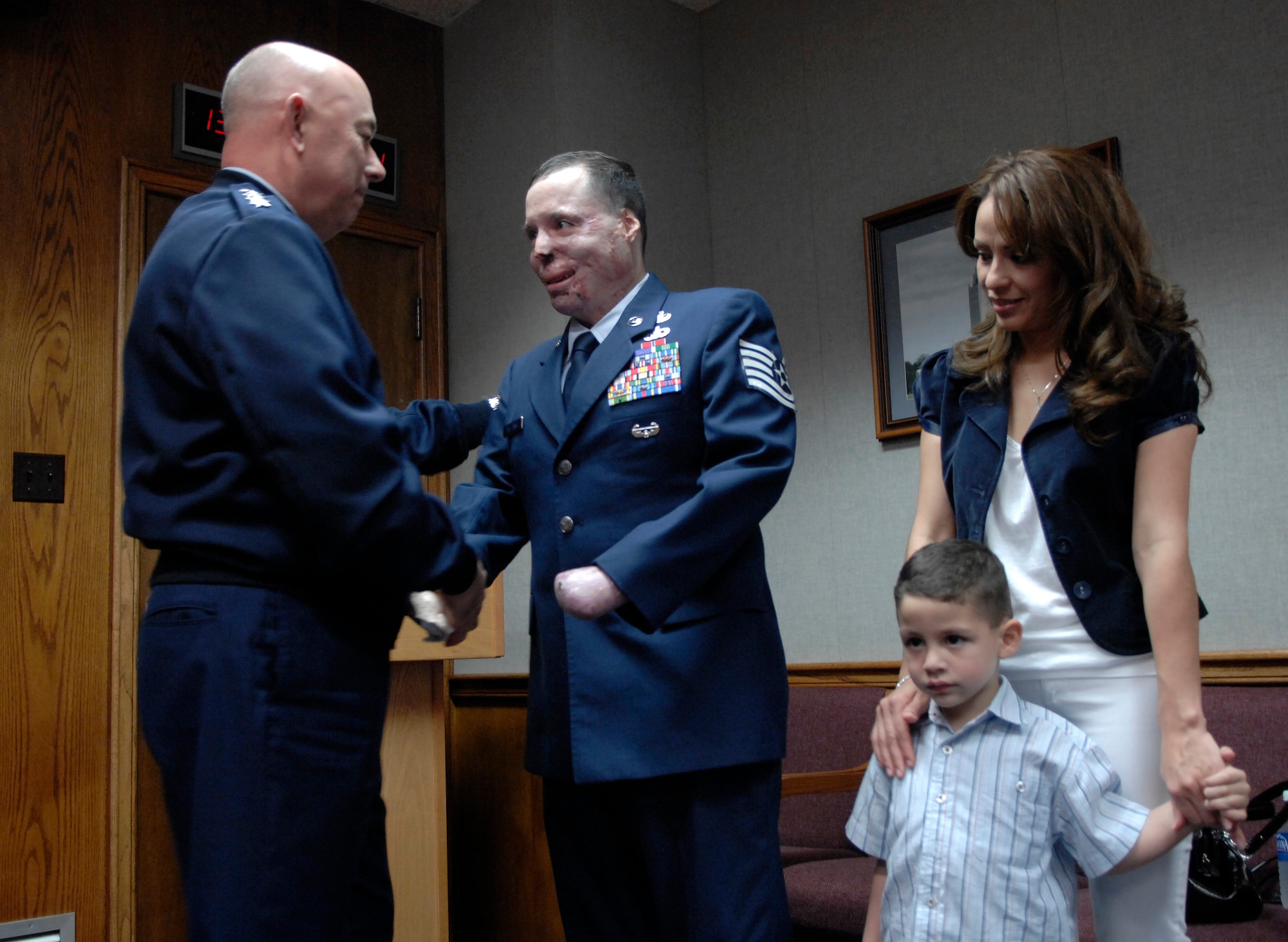 Air Force Chief of Staff Gen. T. Michael Moseley congratulates Tech. Sgt. Israel Del Toro after promoting him at a ceremony at Randolph Air Force Base, Texas, Feb. 22. Part of the small group of guests at the event were the sergeant's wife, Carmen, and son, Israel. The sergeant received burns over more than 80 percent of his body while on a combat patrol in Afghanistan in December 2005. (U.S. Air Force photo/Staff Sgt. Brian Ferguson)