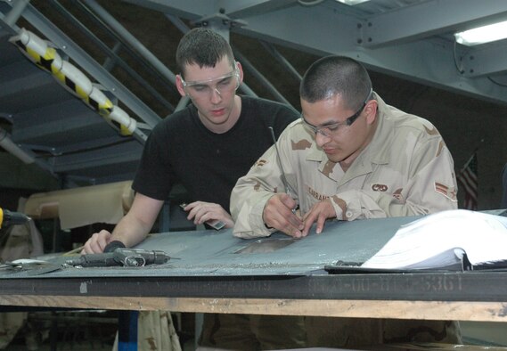 Senior Airman Ryan VanArtsdalen (left) and Airman 1st Class Jaime Carranza (right), 379th EMXS aircraft structural maintenance journeymen, repair a No. 2 spoiler off of a KC-135 Stratotanker. (U.S. Air Force photo by Senior Airman Erik Hofmeyer)
