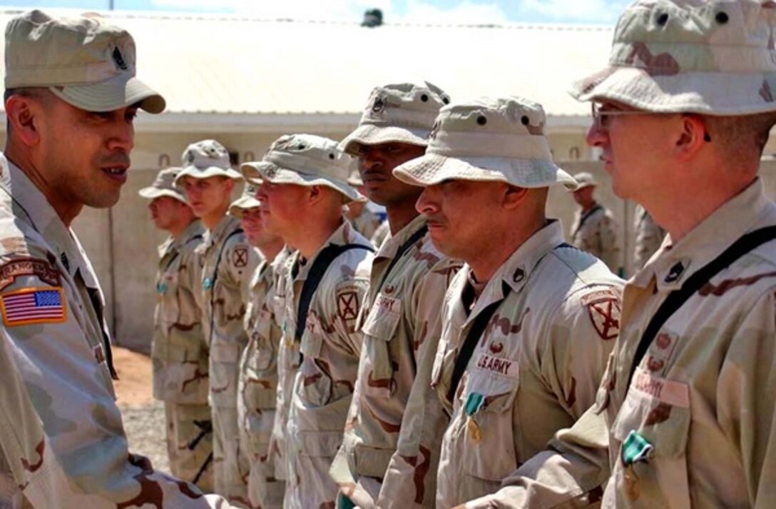 Command Sgt. Maj. Ralph Borja, 10th Mountain Division command sergeant major, congratulates Sgt. 1st Class Michael Carlan and other soldiers from 2nd Battalion, 15th Field Artillery Regiment, at their April 5 award ceremony for rescuing two Egyptian hostages from terrorists Feb. 7.