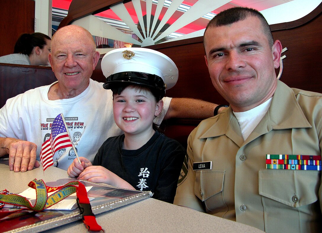 Michaela Bennett, 8, and her grandfather, former Marine and 30-year veteran Bob Mason, join and Marine Corps Staff Sgt. Ramiro Leiva of Marine Recruiting Substation Chantilly, Va., during the Kids Night letter writing campaign at the Silver Diner in Fairfax, Va., April 5. Photo by Sgt. 1st Class Doug Sample, USA