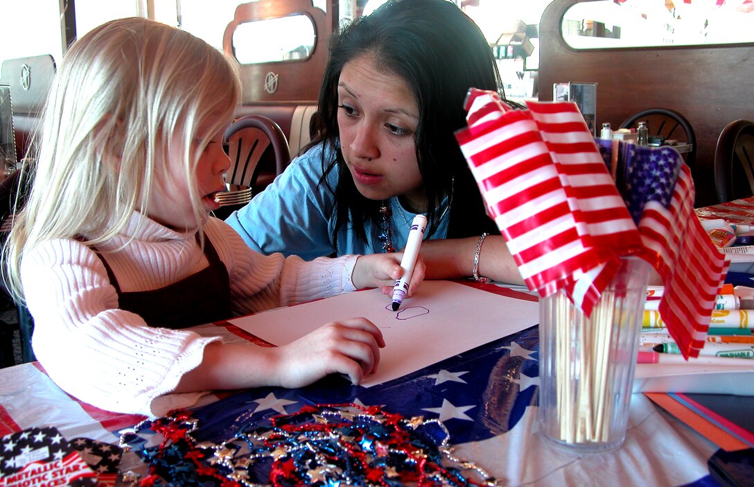 Noelle Buice, 4, composes a letter with the help of Gloria Cuyutupac, a hostess at the Silver Diner in Fairfax, Va., April 5. Noelle was one of several students who came to write letters of support for the troops overseas. Photo by Sgt. 1st Class Doug Sample, USA