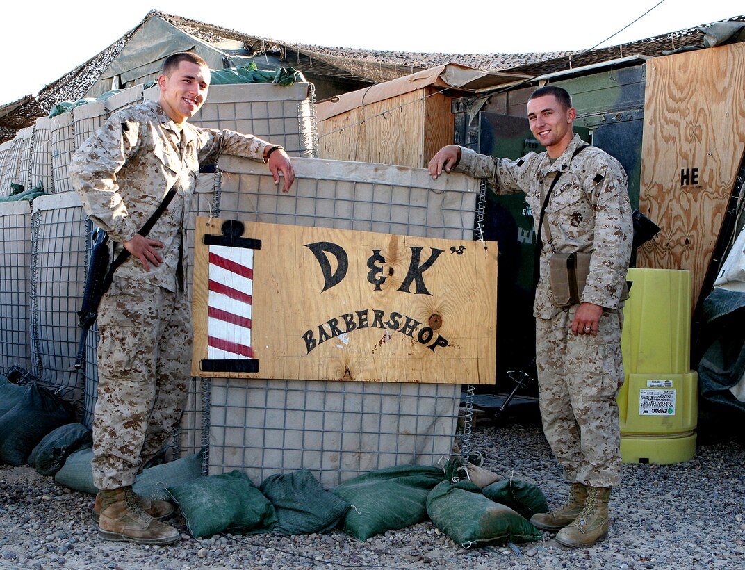 Marine Cpls. Dustin C. (left) and Kyle R. Hanson pose next to a sign for their makeshift barber shop at Camp Fallujah, Iraq. The 21-year-old identical twins are serving together as heavy equipment operators with Engineer Platoon, Charlie Company, 8th Communication Battalion, 2nd Marine Expeditionary Force, Headquarters Group, 2nd MEF (Forward). Photo by Staff Sgt. Ronna M. Weyland, USMC