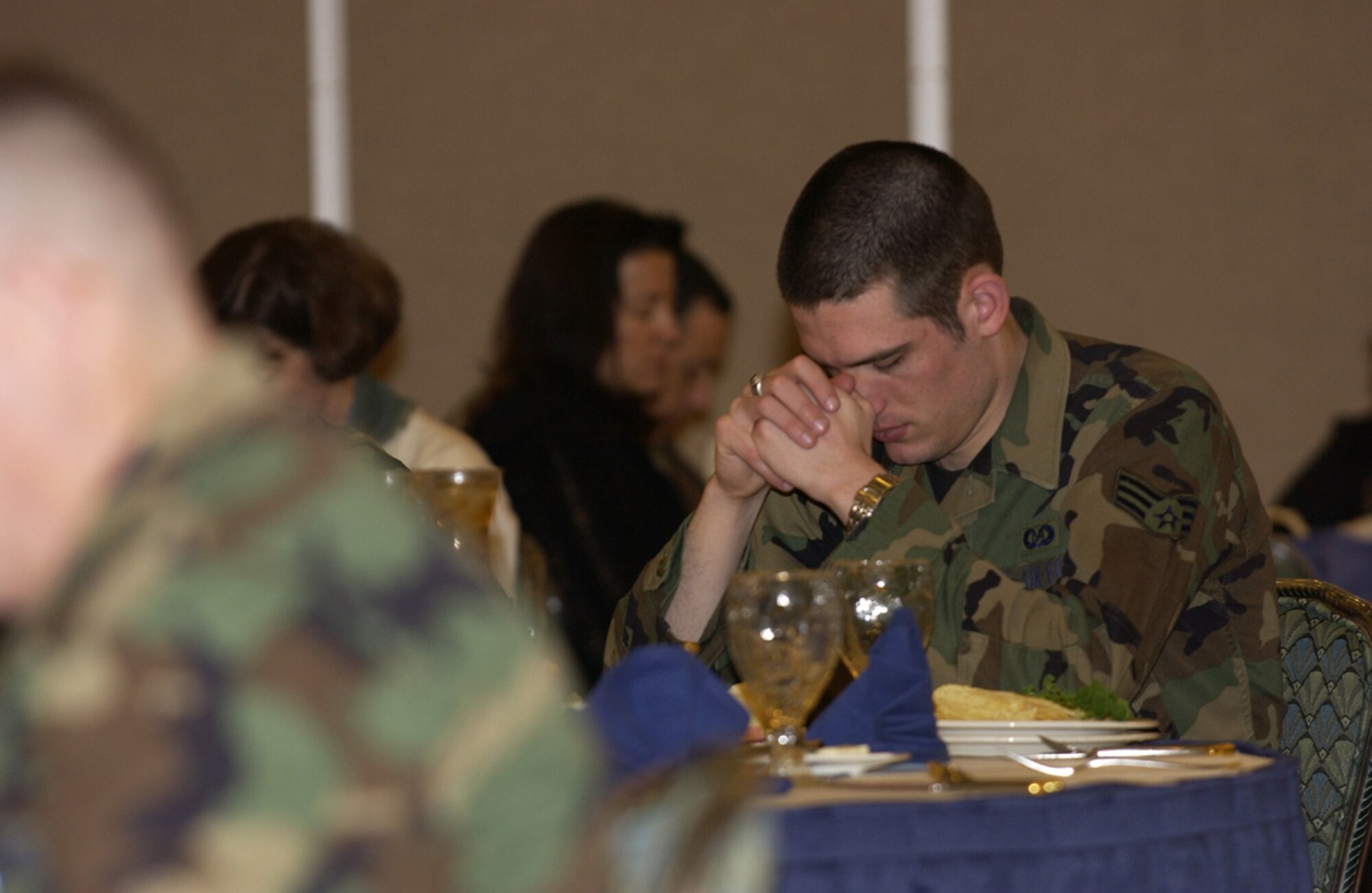 070222- MISAWA AIR BASE, Japan -- An Airman bows his head during prayer at the beginning of Misawa's National Prayer Luncheon Feb. 22 here. Nearly 200 service and family members came out to hear the guest speaker, Chaplain (Colone) Robert Bruno, Joint Chiefs chaplain, give a inspirational message. (U.S. Air Force photo by Senior Airman Robert Barnett)