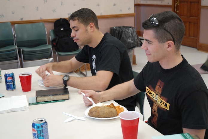 Airman 1st Class James Soto and Airman 1st Class Matt J. Blake, both loadmasters from the 14th Airlift Squadron, enjoy a home-cooked meal at the Airmen's Dinner held at the Chapel Annex Feb. 22.