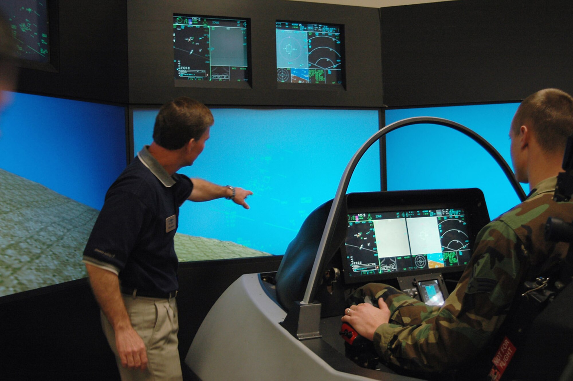 Senior Airman Brian Suminski, with 388th FW manpower, maneuvers in the F-35 simulator while Mr. Mike Barton, a senior staff engineer with Lockheed Martin, guides him on how to fly the aircraft Feb. 22.