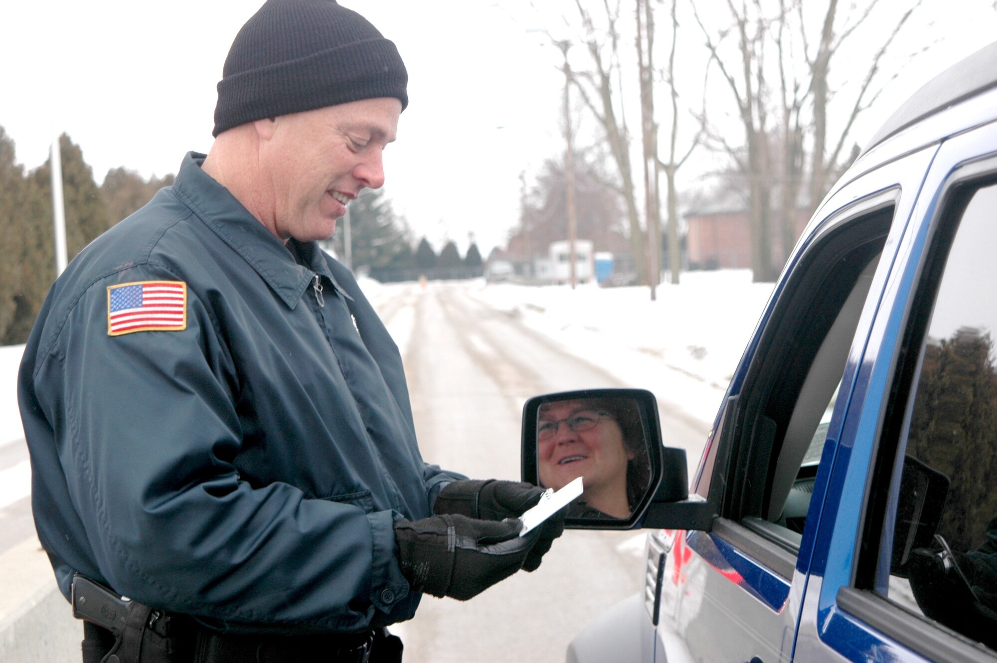 GRISSOM AIR RESERVE BASE, Ind., -- Tim Spangler, 434th Security Forces Squadron, checks the identification of Cathy Clark, 434th Communications Squadron as she enters the base at the North Gate. Grissom's team of civilians, active duty (AGR) and traditional reservists all worked together to help the 434th SFS win the Air Force Outstanding Security Forces Reserve Unit Award for 2006. (U.S. Air Force photo/Tech. Sgt. Doug Hays)