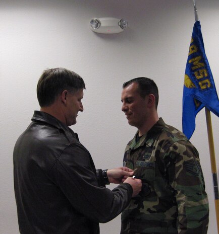 Col. Michael Bartley, 99th Air Base Wing commander, presents Staff Sgt. Javier Lucero, 99th Logistics Readiness Squadron aircraft transportation specialist, with the Purple Heart Medal during a ceremony Feb. 16. Sergeant Lucero was in Sather Air Base, Iraq, when he was injured by a mortar shell at Camp Victory while with a group of four other servicemembers. (U.S. Air Force photo/Tech. Sgt. Louie Arevalo)