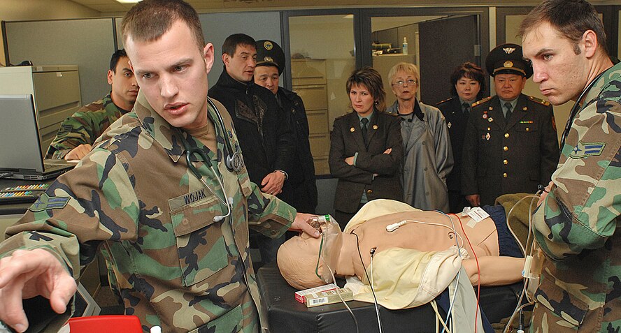 Airman 1st Class Tom Wojak and Airman 1st Class Asher Woodhouse, both from the pararescue school here, perform a medical emergency scenario while foreign military officials watch and ask questions. (U.S. Air Force photo by Todd Berenger)