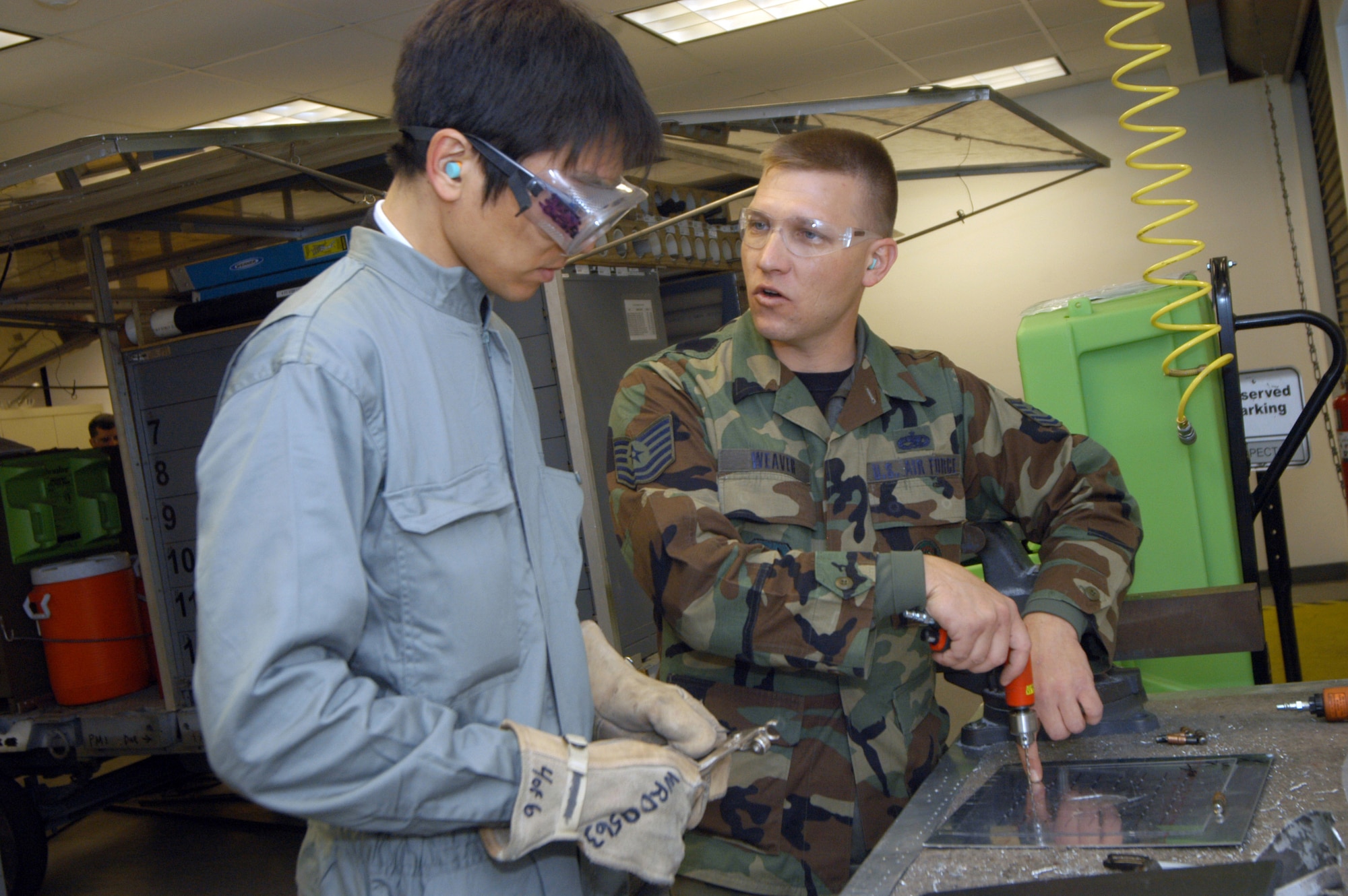 Tech. Sgt. Glen Weaver demonstrates a battle damage repair technique to Tomohiro Matsuo Feb. 14.  Five members of the Japan Air Self-Defense Force visited Robins Air Force Base, Ga., to improve their battle-damage repair skills.  Sergeant Weaver is with the 653rd Combat Logistics Support Squadron.  (U.S. Air Force photo/Sue Sapp)