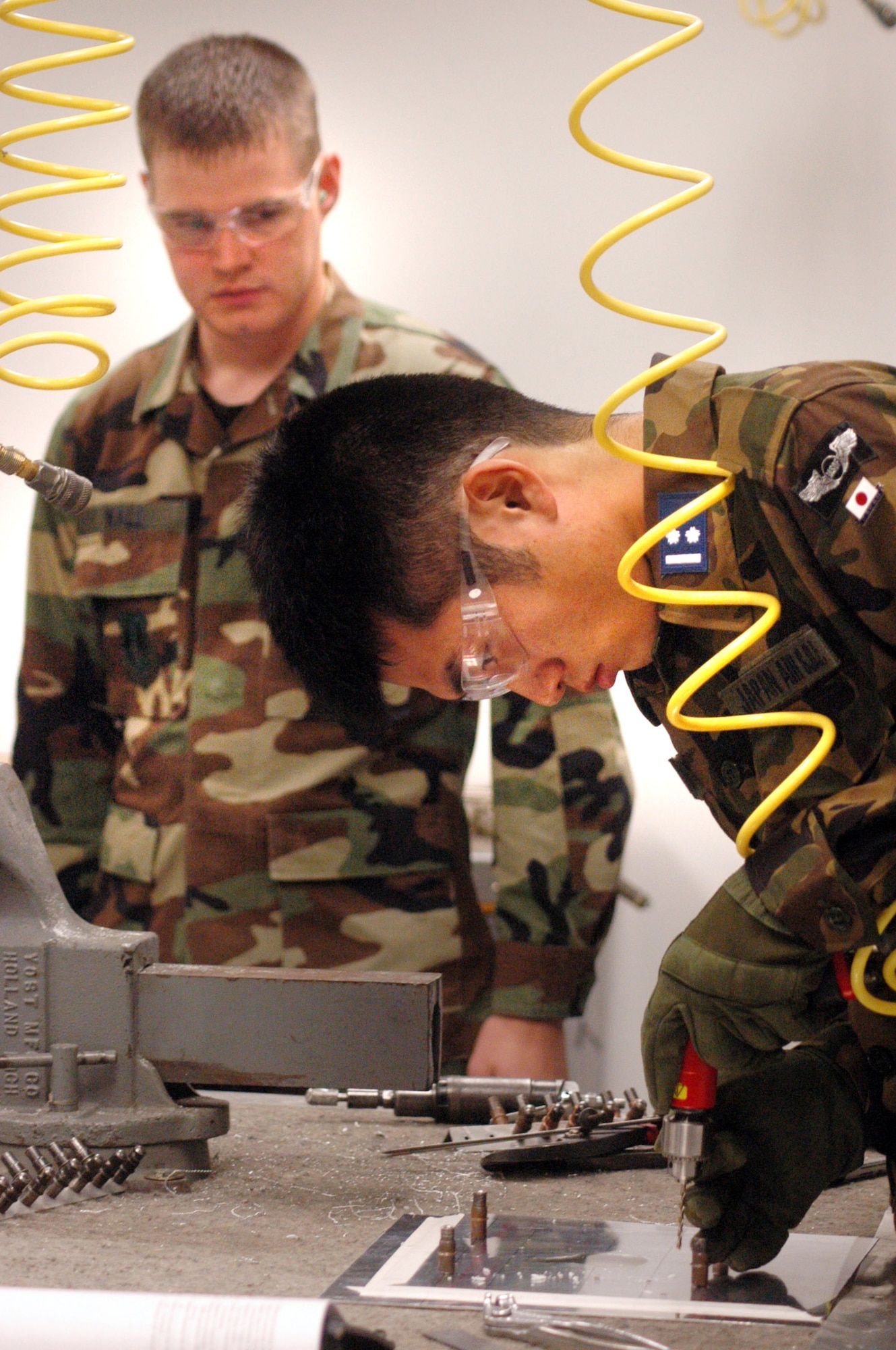 Staff Sgt. Jacob Wall observes as 1st Lt. Yusuke Asano repairs a piece of sheet metal with simulated battle damage Feb. 14.  Five members of the Japan Air Self-Defense Force visited Robins Air Force Base, Ga., to improve their battle-damage repair skills.  Sergeant Wall is with the 653rd Combat Logistics Support Squadron.  (U.S. Air Force photo/Sue Sapp)