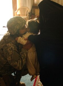 Master Sgt. Coco Gunther, 1st Combat Camera Squadron videographer, gives an Iraqi baby a kiss during a combined cordon and search with the Iraqi National Police in the Ur area of Baghdad, Iraq, Feb. 14. (U.S. Army photo by Sgt. Tierney Nowland)