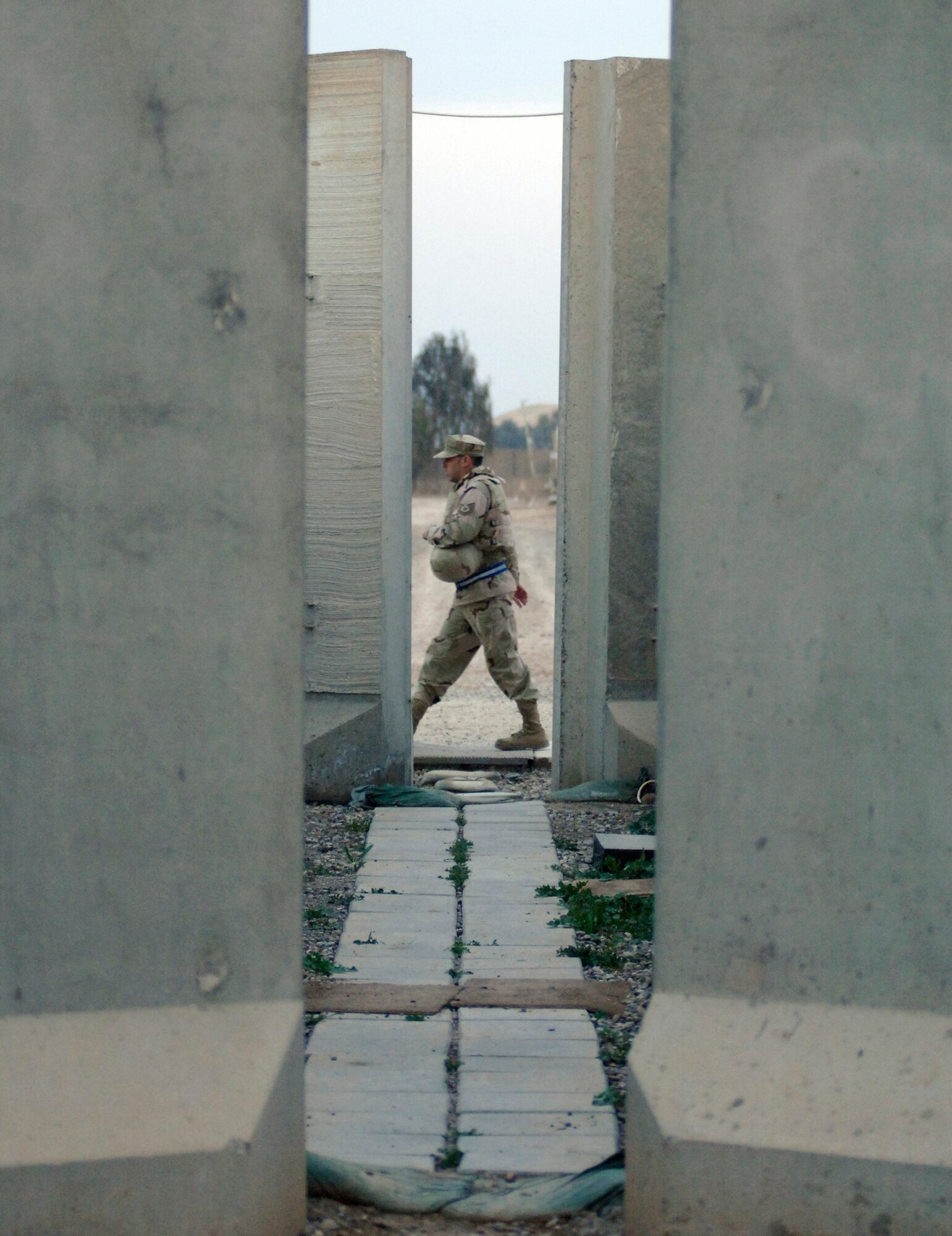 An Airman walks between a row of large T-barriers Feb. 21 at Balad Air Base, Iraq.  Most Airmen assigned to the base live in a compound surrounded by towering T-barriers. They act as a line of defense against stray bullets and blast protection from mortar attacks. The weight of the T-barriers varies from four to 17 tons. The T-barriers' purpose is to protect all base facilities.  This intricate network of pathways serves as a shield for more than 3,300 Airmen. (U.S. Air Force photo/Tech. Sgt. Cecilio M. Ricardo Jr.)