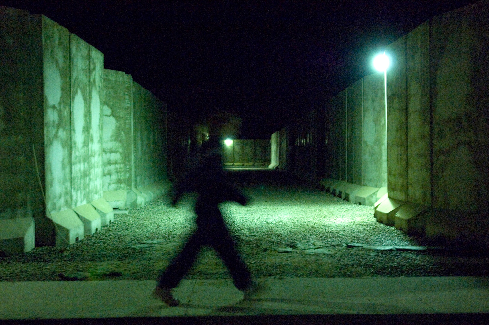 An Airman walks back to her room Feb. 21 at Balad Air Base, Iraq.  Most Airmen assigned t0 the base live in a compound surrounded by towering T-barriers. They act as a line of defense against stray bullets and blast protection from mortar attacks. The weight of the T-barriers varies from four to 17 tons. The T-barriers' purpose is to protect all base facilities. This intricate network of pathways serves as a shield for more than 3,300 Airmen. (U.S. Air Force photo/Tech. Sgt. Cecilio M. Ricardo Jr.)