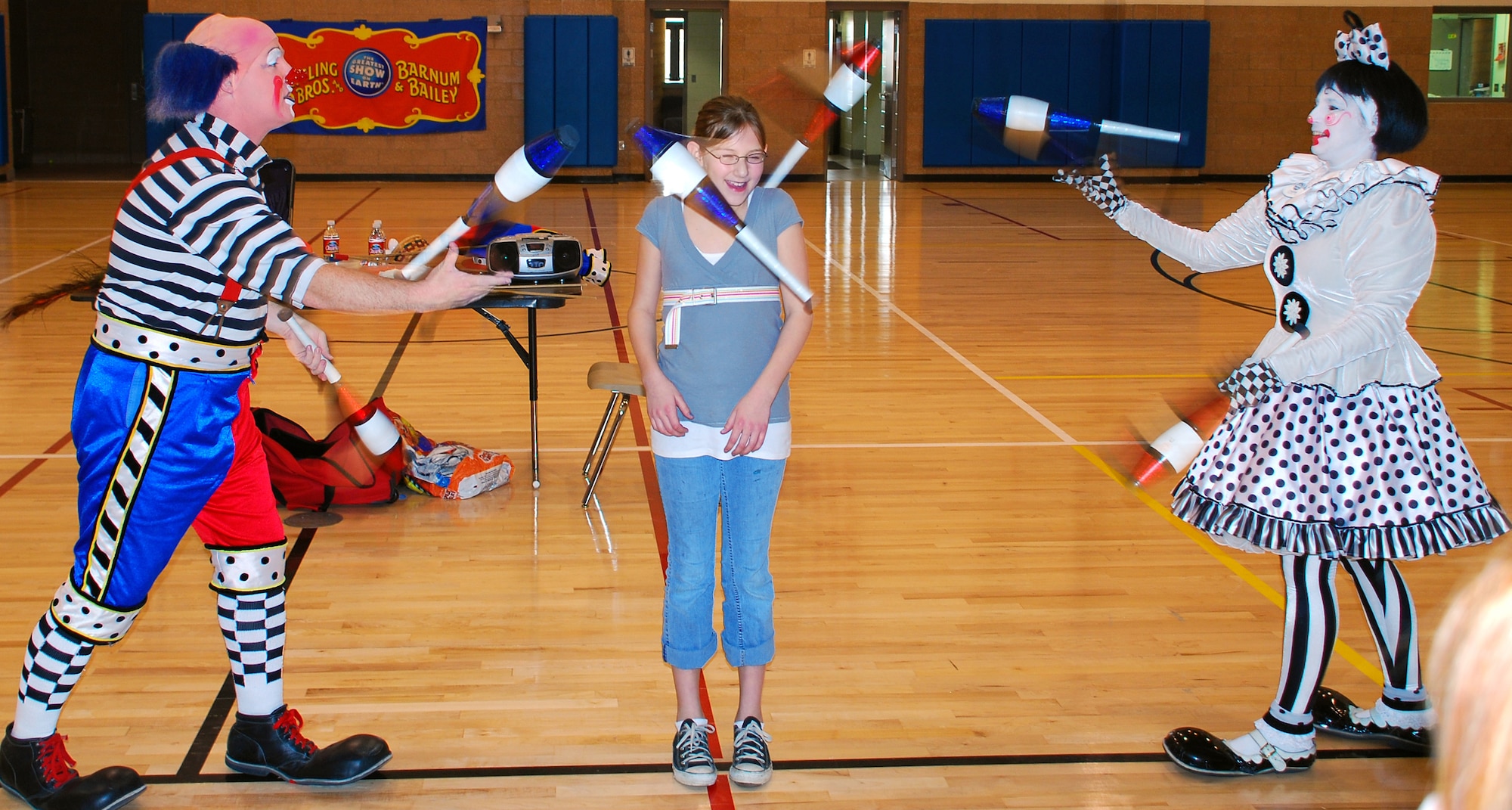 Imani Pirrie stands very still while Cherie and Dave Gregg, Goodwill Ambassador Clowns with Ringling Bros. and Barnum & Bailey Circus strategically juggle pins around her. Cherie and Dave performed their Circus Science show Feb. 24 for Sheppard children at the Madrigal Youth Center. (U.S. Air Force photo/Tech. Sgt. Jennifer Isom)