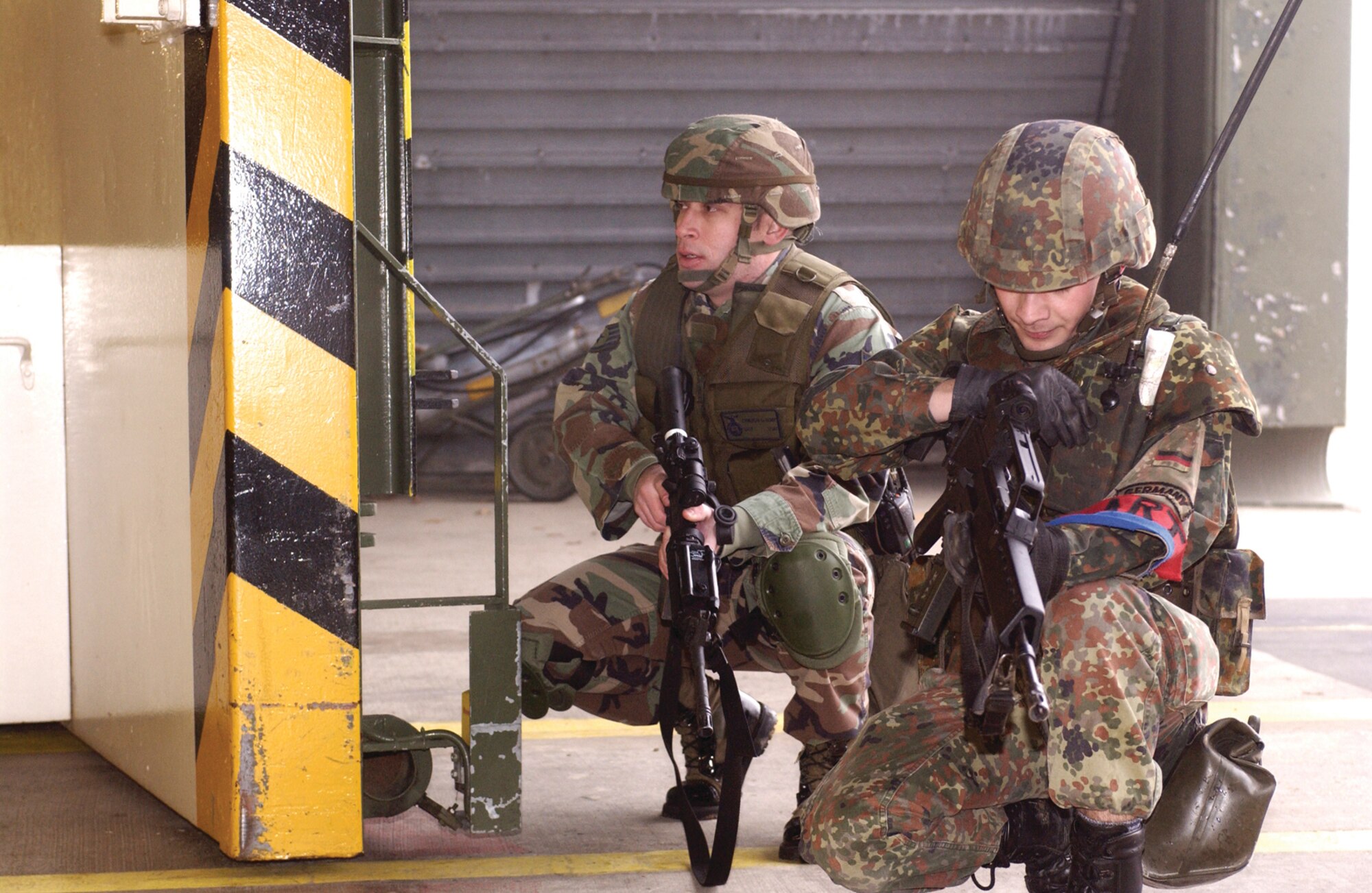 Staff Sergeant Cameron Kemp, 702nd Munitions Support Squadron Security Forces Operations, Buechel Air Base, Germany, covers a German air force member while he simulates firing into a protected aircraft shelter. The Airman are working together to recapture the PAS which has been overtaken by terrorists in an exercise, Feb. 21, 2007.  (U.S. Air Force photo by Senior Airman Kristin Ruleau) 