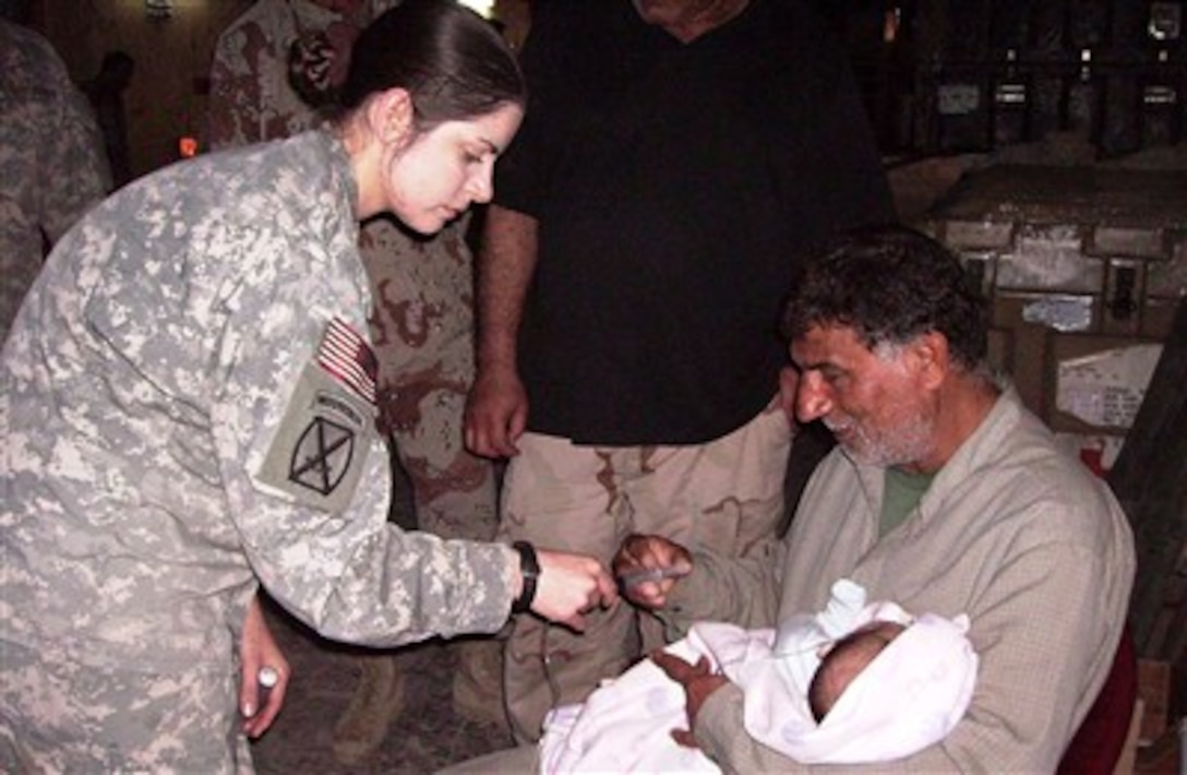U.S. Army Spc. Carrielynn Spillis (left), a medic assigned to the 210th Brigade Support  Battalion “Providers,” 2nd Brigade Combat Team, 10th Mountain Division (Light Infantry), shows Nasseir Alaobed how to care for his infant son at the Patrol Base Yusufiyah aid station in Yusufiyah, Iraq, Feb. 21, 2007.