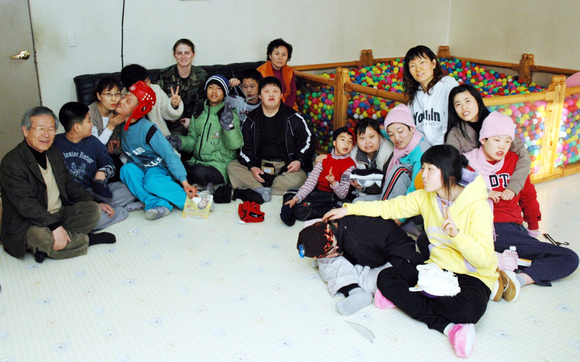 PYONGTAEK, Repulic of Korea --  Senior Airman Kristine Crawley, 51st Maintenance Squadron, (center), spent time with children and adults at a Korean school for the deaf in Pyongtaek on Feb. 1.  Airman Crawley presented enough winter gloves, hats, mittens, scarves and slippers to cloth two dozen people on behalf of the Lt. Col. (retired) Clete Knaub family in Laurel, Mont. (U.S. Air Force photo by Tech. Sgt. Michael O’Connor)