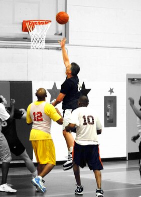 EGLIN AIR FORCE BASE, Fla. -- Keith Howard, Air Armament Center, shoots a layup while Robert Taylor (12), 96th Medical Group, watches on form inside the paint during the Over 30 Basketball Champinoships Feb. 21. The Med Group forced a second game in the double-elimination tournament held at the main fitness center with a 43-37 win. The AAC won the tournament in a decisive final game 61-53 to claim the champinoship. (U.S. Air Force photo/Will Vandermate)