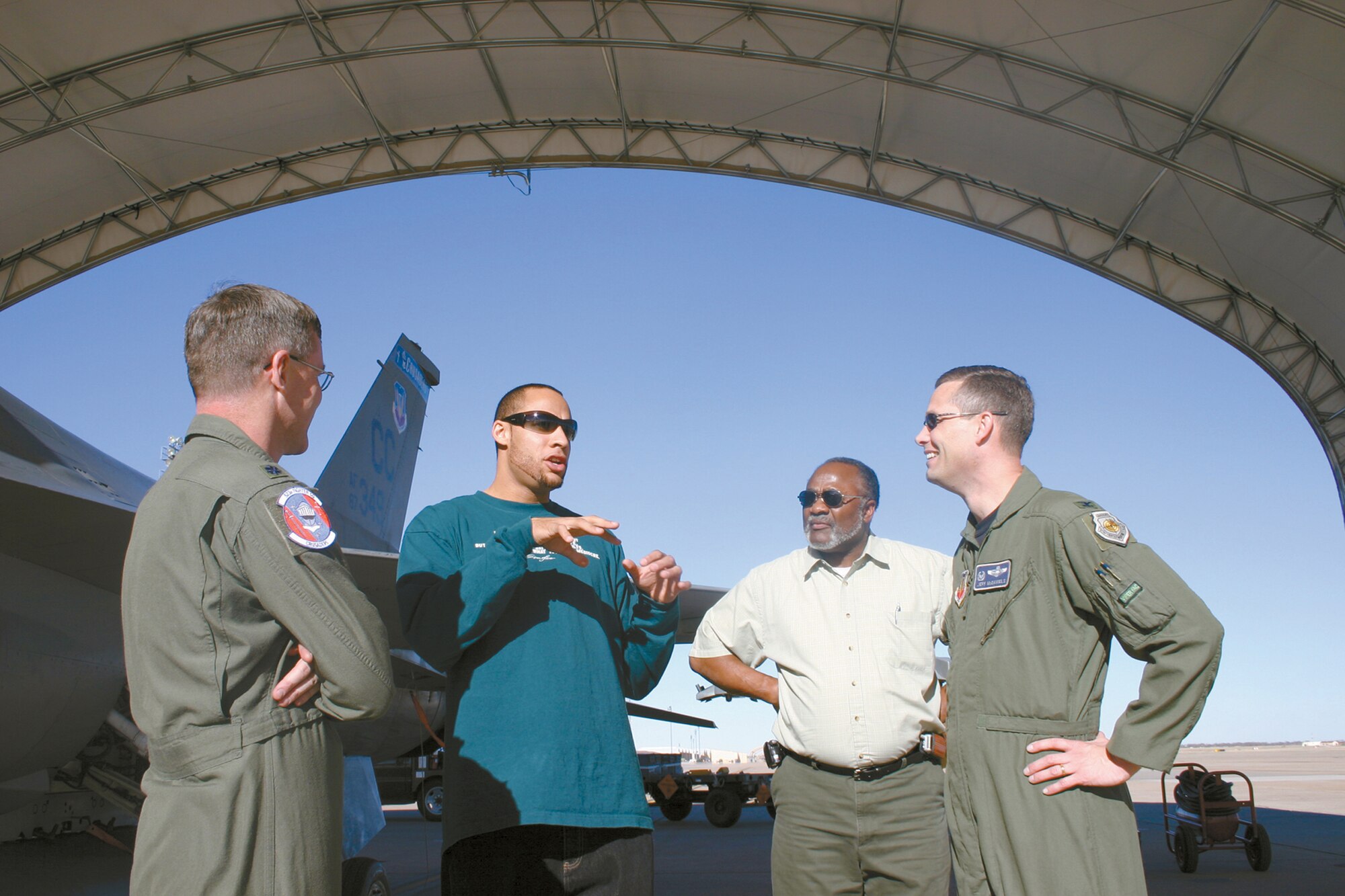 Lt. Col. Brad Kearney; 523rd Fighter Squadron commander and Col. Jeff McDaniel, 27th Operations Group commander at Cannon Air Force Base, N.M., listen as Hank Baskett III (second from left) explains how the sound of an F-16 flying overhead compares with the sound of the crowd at a football game. Hank and his father, retired Chief Master Sgt. Hank Baskett Jr. (second from right) toured the 523 FS and the flight simulator on Feb. 21. The retired chief's  son finished his first National Football League season with the Philadelphia Eagles as a wide receiver where he received the Rookie of the Week award twice during the season. (U.S. Air Force photo by Janet Taylor-Birkey)