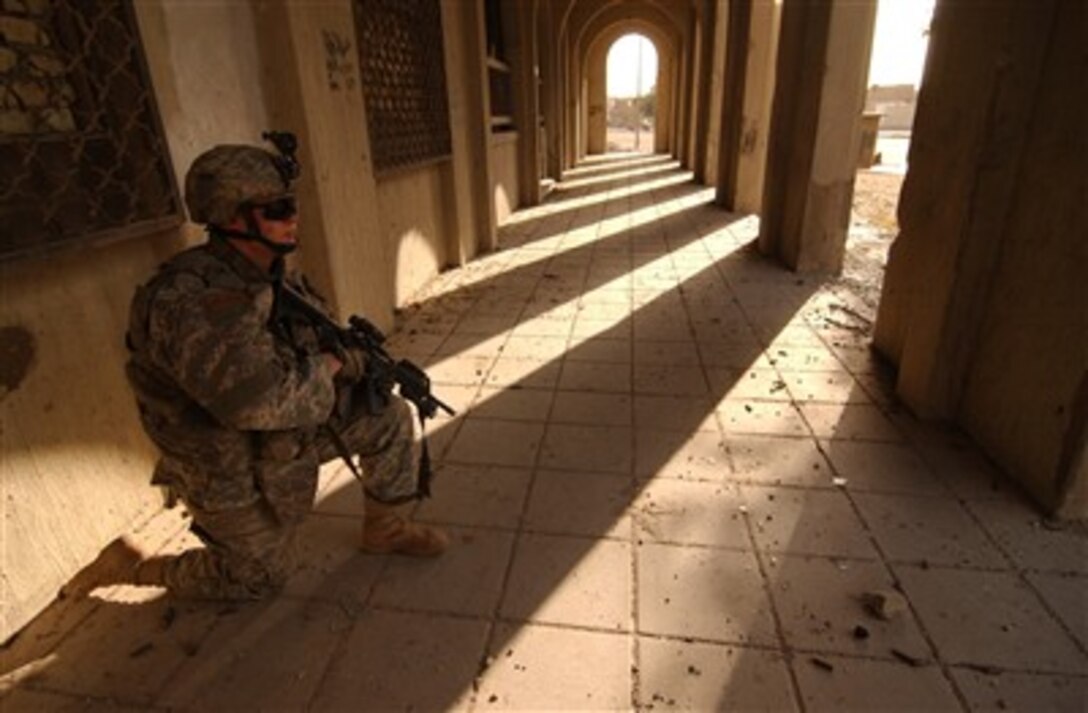 U.S. Army Spc. Gilad Wolbe takes a knee in the shadows while he provides security during a humanitarian aid mission in Baghdad, Iraq, on Feb. 26, 2007.  Wolbe is with Delta Company, 2nd Battalion, 12th Infantry Regiment, 2nd Brigade Combat Team, 2nd Infantry Division.  