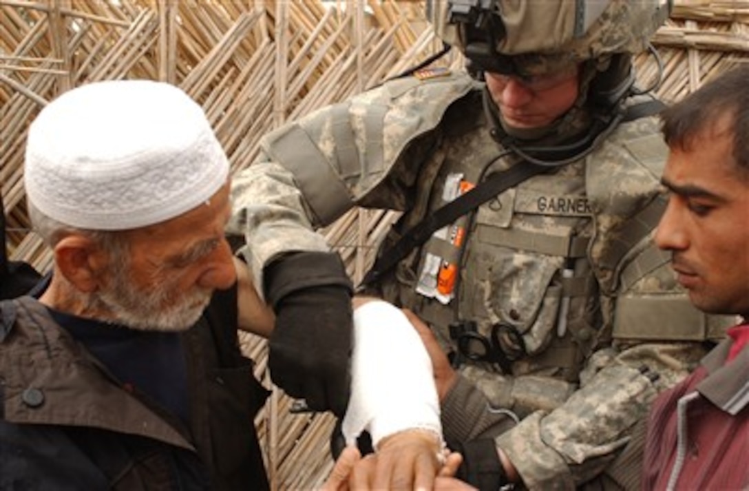 U.S. Army Medic Pfc. Michael Garner splints an elderly man's arm during a humanitarian assistance mission on Haifa Street in Baghdad, Iraq, on Feb. 13, 2007.  Garner is attached to Charlie Troop, 4th Squadron, 9th Cavalry Regiment, 2nd Brigade Combat Team, 1st Calvary Division.  