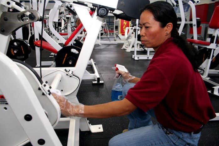 Prakai Parsons, IronWorks Gym recreation attendant and Sakon Nakhon, Thailand, native, polishes gym equipment before service members begin their morning workout. Parson?s two years of outstanding customer service has earned her the 2007 Front Line award from the Armed Forces Recreation Society.