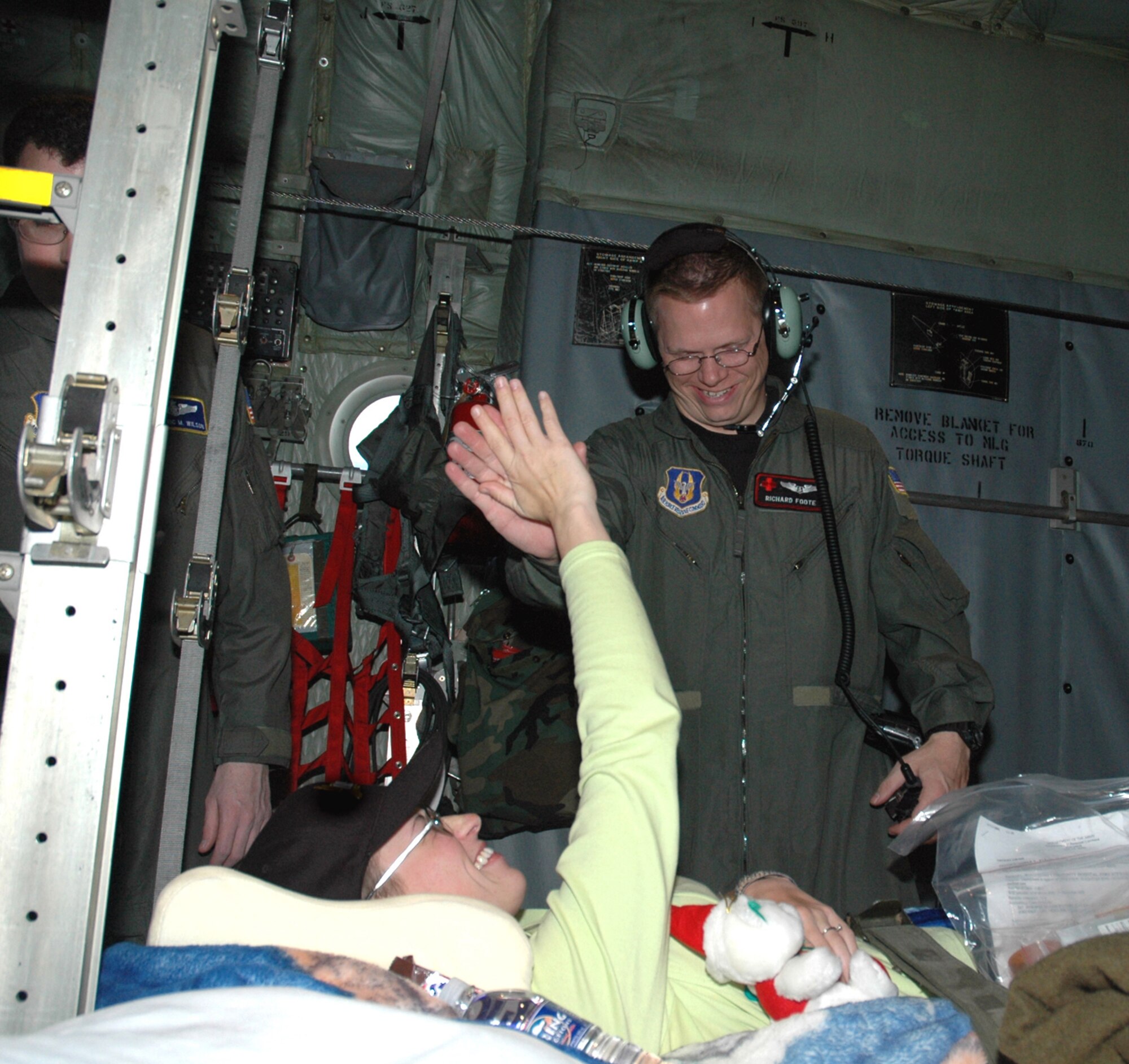 Capt. Richard Foote gets a high five from Army Pvt. Amber Zeunen as she is transported home aboard a C-130 Hercules. Private Zeunen was injured while serving in Operation Iraqi Freedom. Captain Foote is an Air Force Reserve Command flight nurse with the 908th Airlift Wing at Maxwell AFB, Ala. (U.S. Air Force photo/Lt. Col. Jerry W. Lobb)