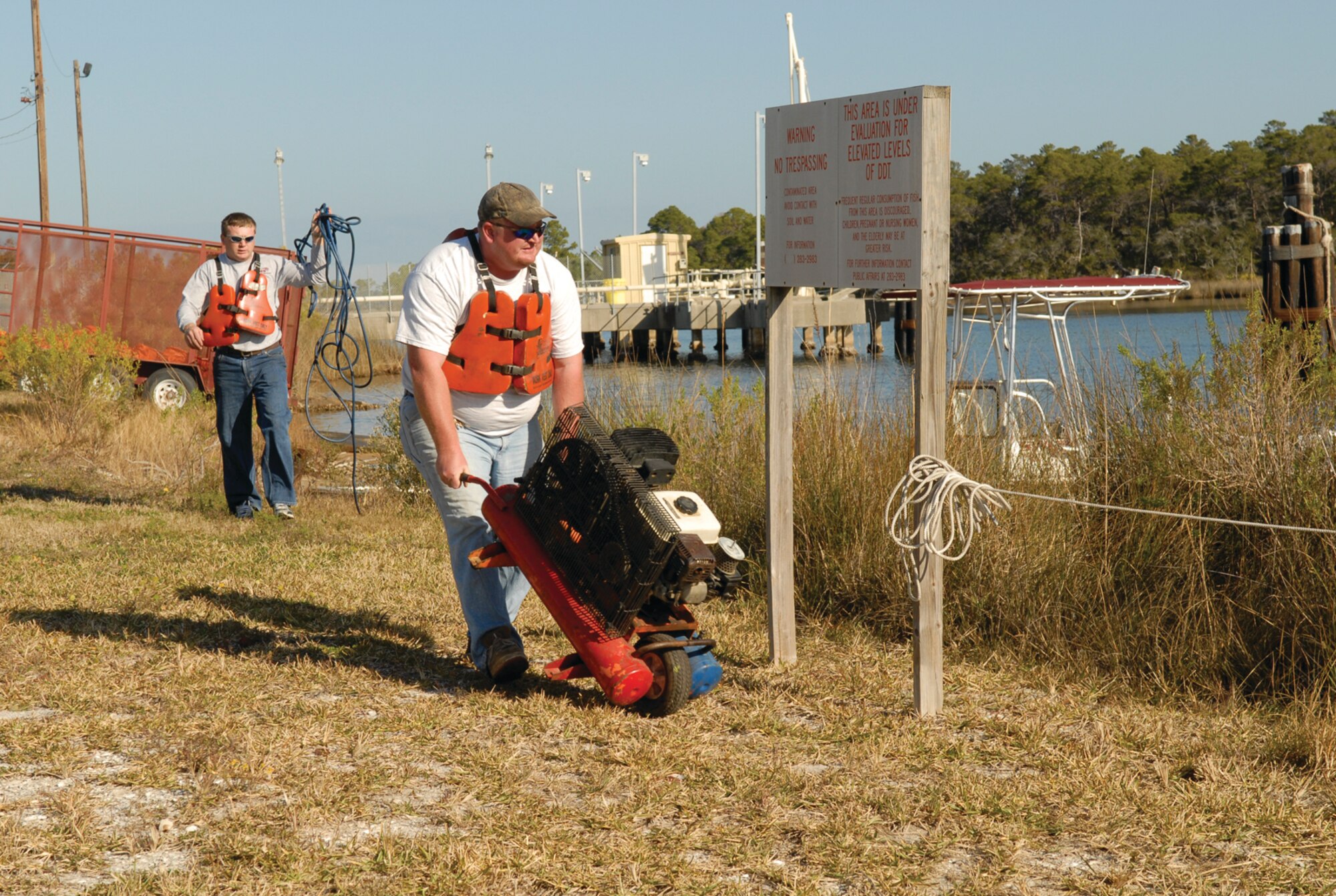 A response team member moves an air compressor to the spill site to assist spill control and recovery operations. 