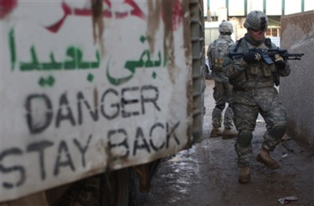 U.S. Army Staff Sgt. Chance Seidell walks behind a Stryker vehicle during a cordon and knock operation outside of Sadar City, Iraq, on Dec. 24, 2006.  Seidell is attached to Bravo Company, 1st Battalion, 23rd Infantry Regiment, 3rd Stryker Brigade Combat Team, 2nd Infantry Division.  