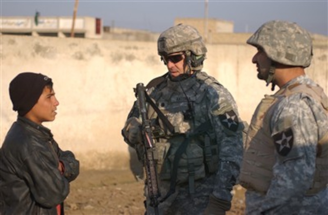 U.S. Army Lt. Col. Bruce Antona, center, battalion commander, 5th Battalion, 20th Infantry Regiment, 3rd Stryker Brigade Combat Team, 2nd Infantry Division, speaks to an Iraqi boy during a cordon and search operation in the New Baghdad area of East Baghdad, Iraq, Dec. 24, 2006. 