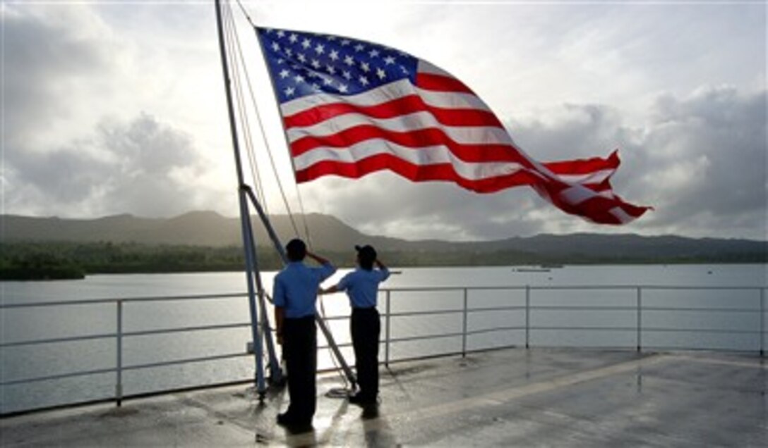 U.S. Navy sailors salute the ensign after bringing it to half-staff in honor of Navy veteran and former President Gerald R. Ford aboard the submarine tender USS Frank Cable (AS 40) in Apra Harbor, Guam, on Jan. 1, 2007.  
