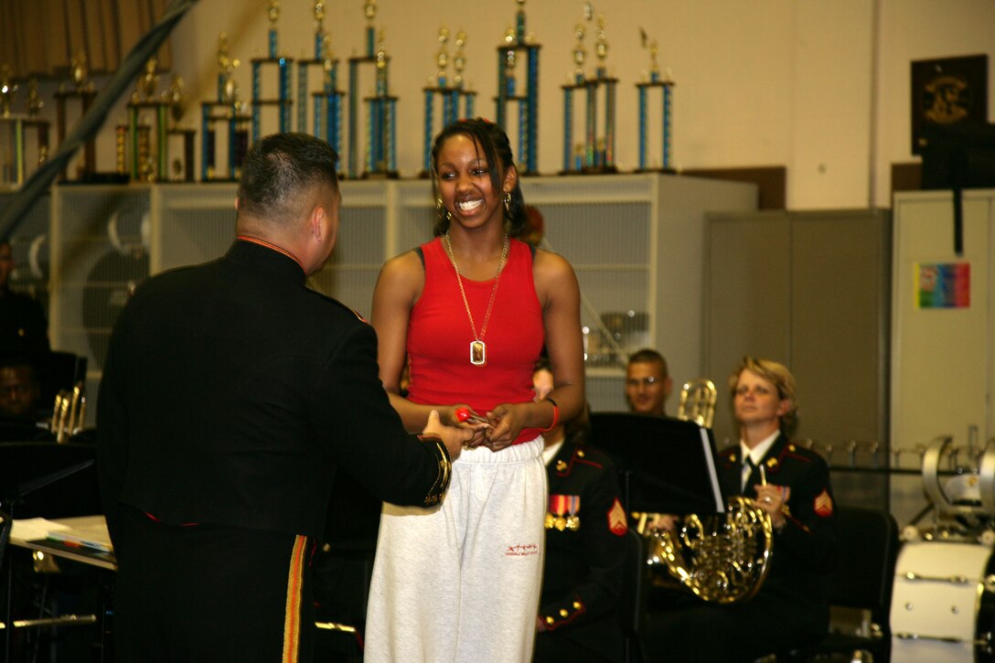 Junior Aqura Lacey is presented an engraved conductor's baton by Parris Island Marine Band director Chief Warrant Officer Christian Flores May 3 during a performance at Dupont Manuel High School's Performing Arts School.  Lacey volunteered to conduct the band, and successfully led them in John Philip Sousa's popular march, The Thunderer.
