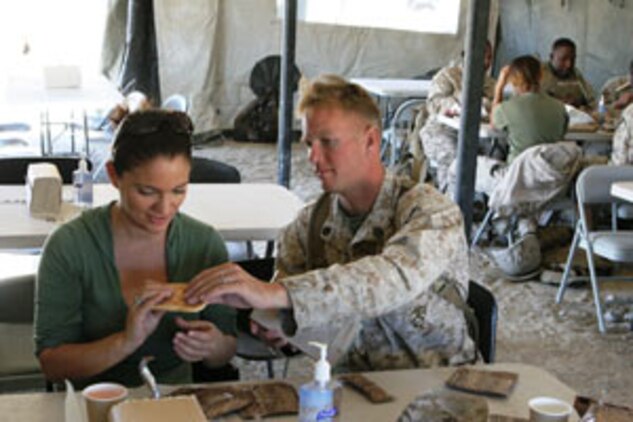 Staff Sgt. Nicholas Macdonald shows his wife, Esther, how to eat the food from a Meal-Ready-to-Eat at the Combat Center?s Range 500 during the 1st Tank Battalion Jane Wayne Day Oct. 4.
