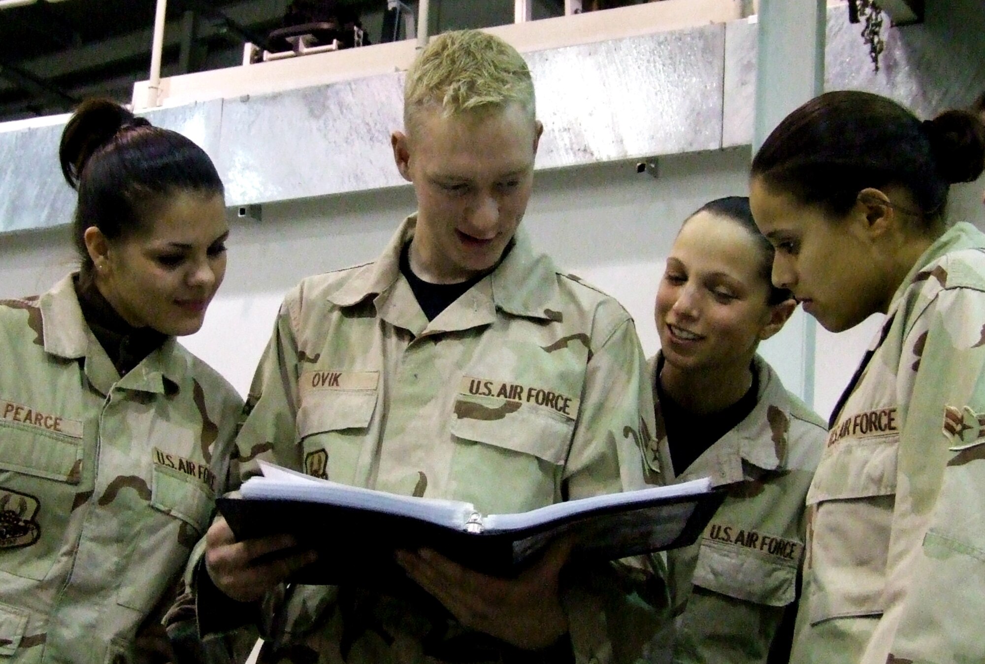 BALAD AIR BASE, Iraq-- (From left to right) Senior Airman Natalie Pearce, Airmen 1st Class Dave Ovik, Brianna Bloomquist and Jessica Canabal examine the book of letters sent by members of the Travis civilian community. Lt. Gen. Gary North, USCENTAF commander, presented the letters to Airmen Dec. 28. All the Airmen are deployed from the 60th Aerial Port Squadron at Travis Air Force Base, Calif. (U.S. Air Force photo by Maj. Richard Sater/332nd AEW Public Affairs)