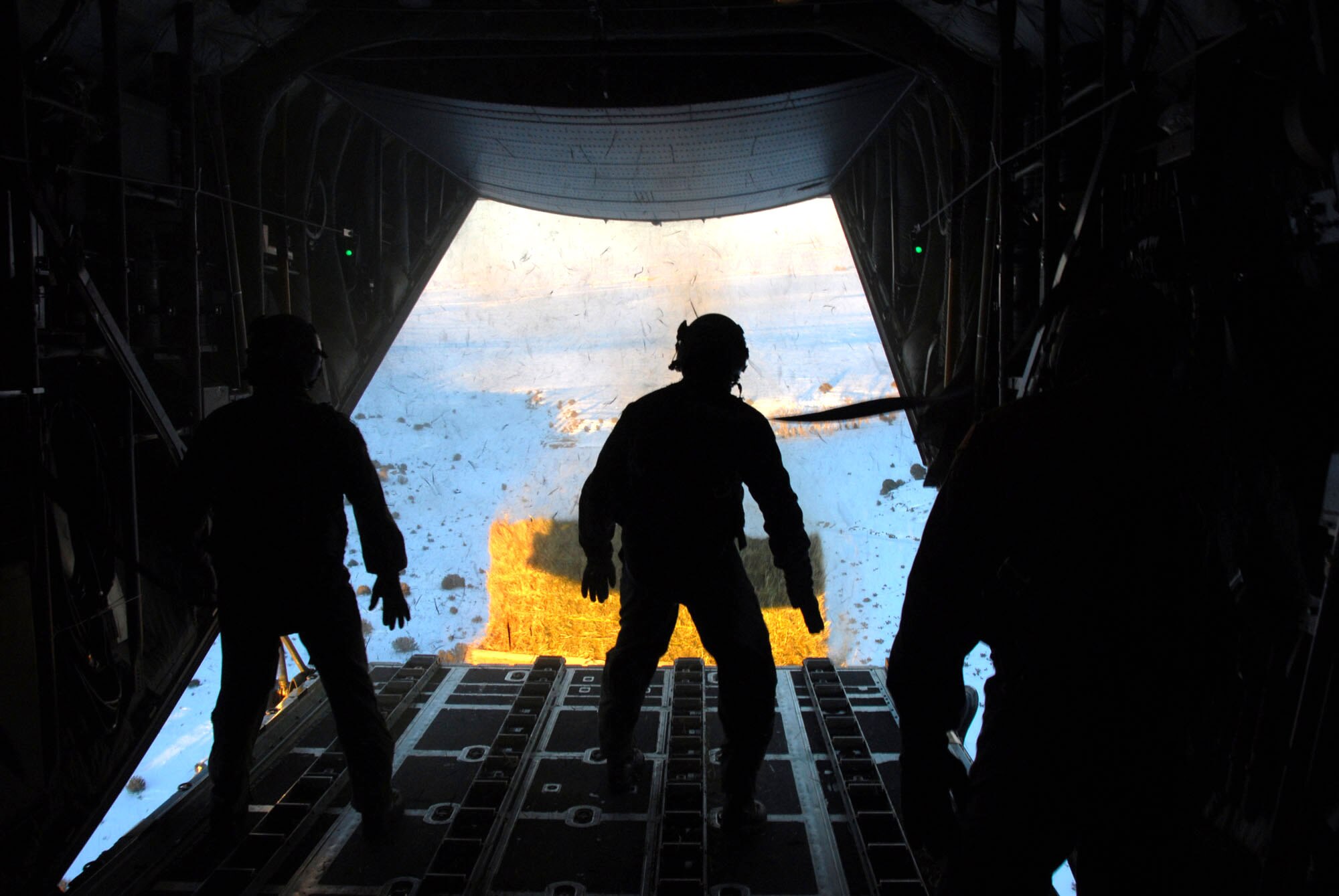 Loadmasters of the Wyoming Air National Guard watch a one-ton hay bale leave their C-130 Hercules aircraft on its way to feed a herd of cattle stranded by a snowstorm in southeastern Colorado Jan. 3. (U.S. Air Force photo/Senior Master Sgt. John Rohrer)
