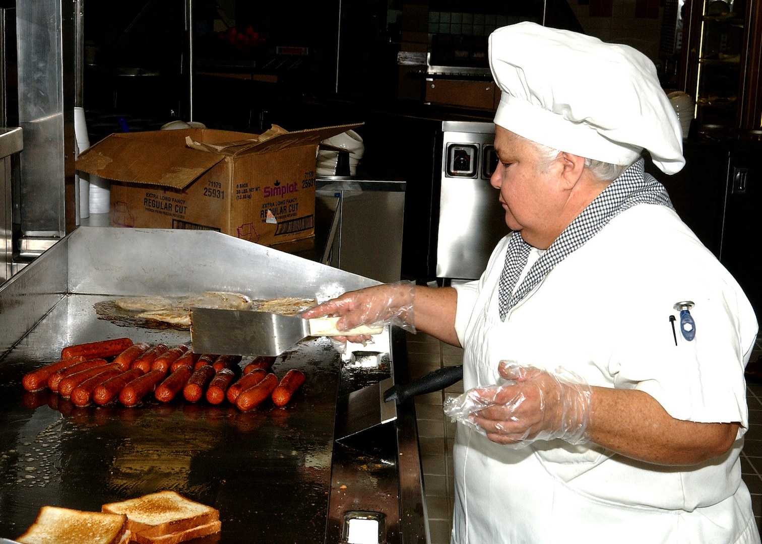 Cathy Aguilar prepares hotdogs, hamburgers, grilled cheese sandwiches and chicken sandwiches Jan. 3, opening day of the newest dining facility on the Lackland Training Annex at Lackland Air Force Base, Texas. The dining facility mainly serves technical students and instructors from the 342nd, 343rd and 344th Training Squadrons, and members of the 90th Intelligence Squadron. The facility can hold up to 1,500 diners, has four serving lines and three dining areas, and has modern lighting and wooden floors. Construction of the dining facility, which replaced the 35-year-old Medina Inn, is among $60.3 million in major building projects scheduled for opening early this year. (USAF photo by Alan Boedeker)                        