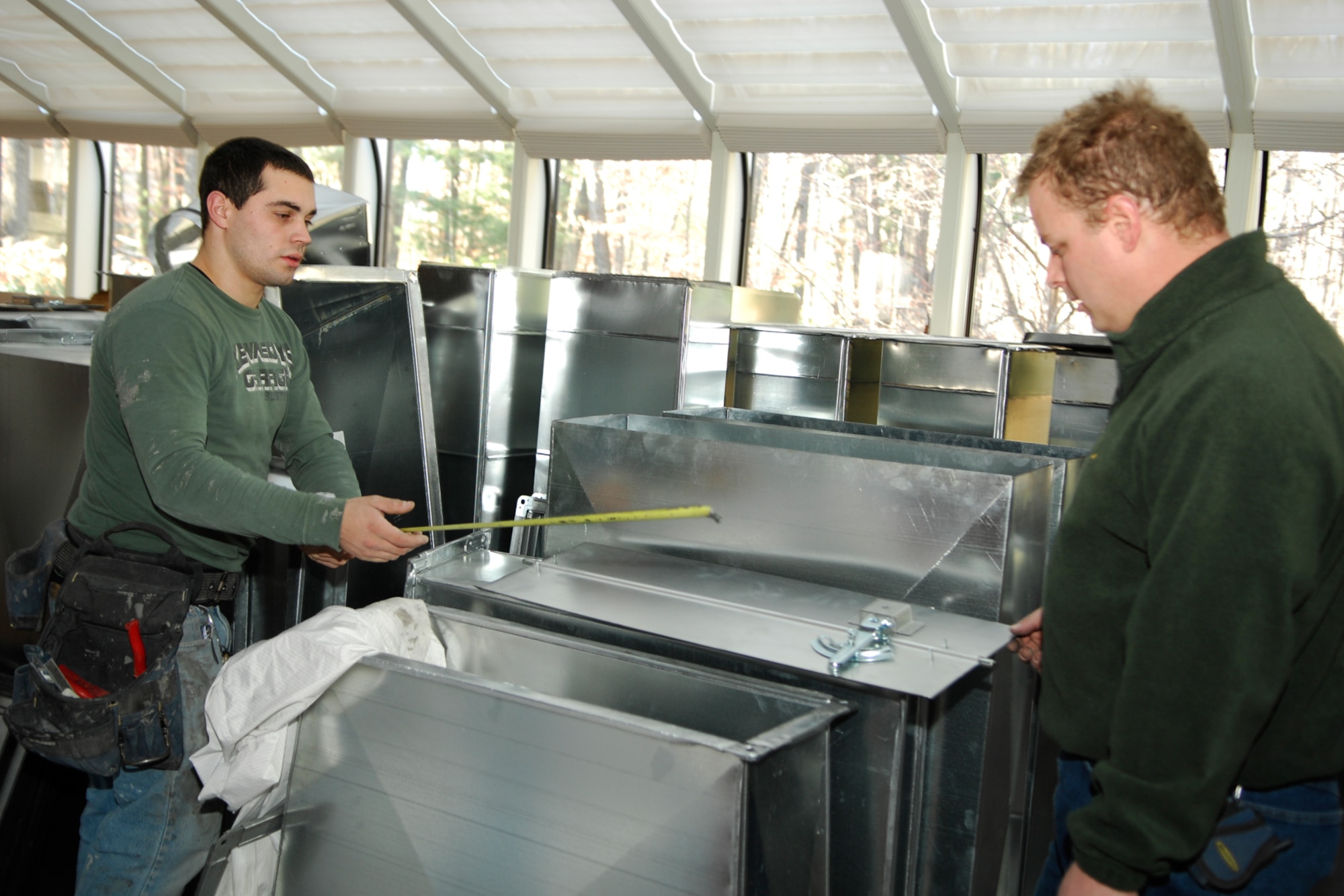 Left, Steve Genailois and Bob Ernst, employees of Horizon Metals located in Tyngsborough, Mass., measure the new heating, ventilation and air conditioning vents installed in the Minuteman Club ballroom on Dec. 29. (US Air Force photo by Jan Abate)