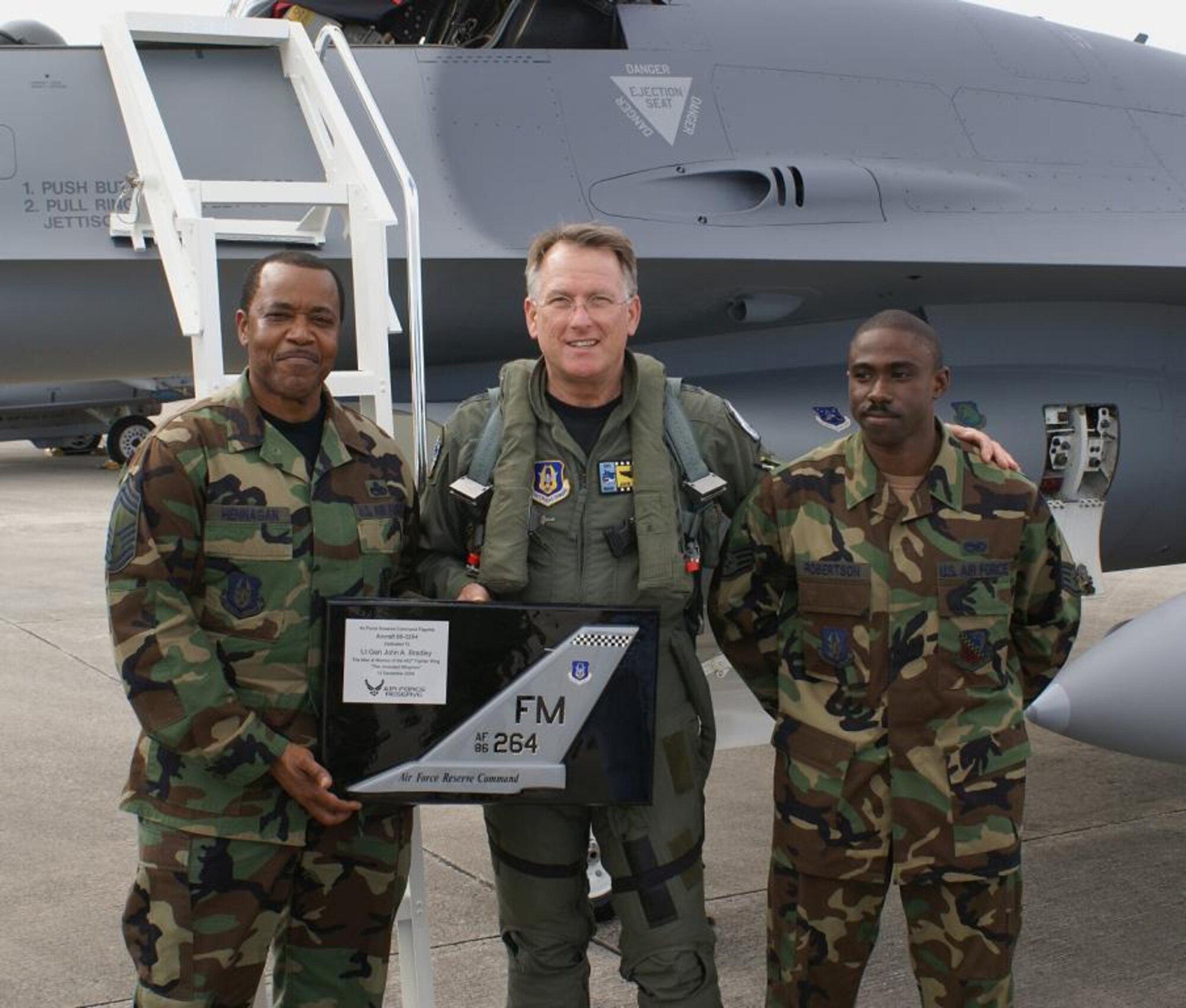 Chief Master Sgt. Fred Hennagan (left) and Staff Sgt. Johnny Robertson (right) present a mounted tail-flash of Aircraft-264 to Lt. Gen. John A. Bradley, Commander of the Air Force Reserve Command and Chief of the Air Force Reserve, Dec. 13 here at Homestead Air Reserve Base, Fla. Airmen of the 482nd Maintenance Group presented and dedicated a “polished” F-16 in his honor. (U.S. Air Force photo/Ryan Ayers)