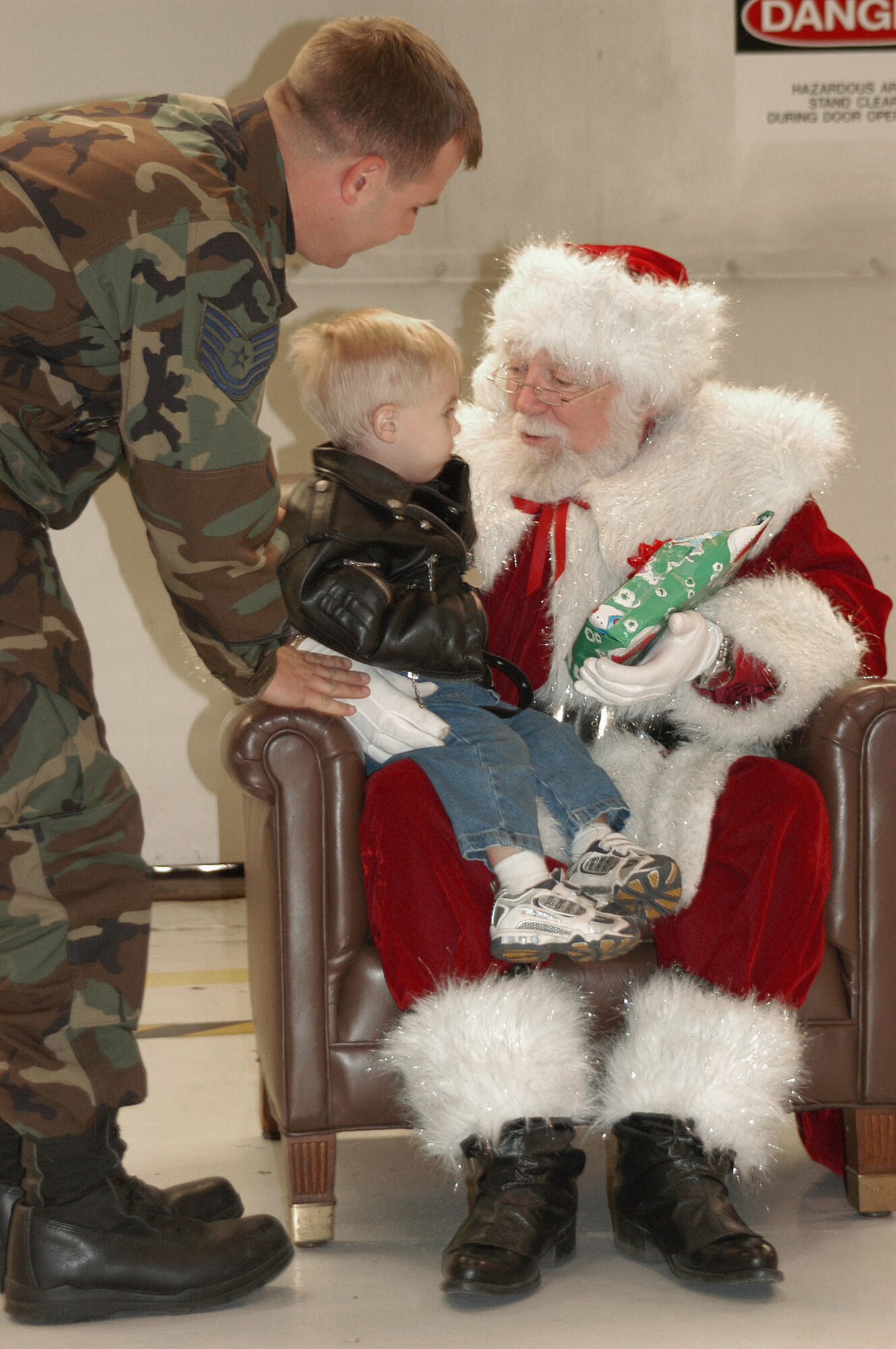Aiden (center) sits on Santa's lap while dad, Tech. Sgt. Denver McCullough, listens in to get some gift ideas. Santa Claus arrived in the back seat of a 457th Fighter Squadron F-16 during December's UTA. Santa was available late Saturday to deliver toys to the boys and girls of the 301st Fighter Wing family. Santa, also known the rest of the year as Dr. Don Shelton, Fort Worth Air Power Council (FWAPC) president, and the FWAPC, an organization that donations to the NAS JRB and 301st Booster Club, help military families in their time of need. (U.S. Air Force Photo/Tech. Sgt. Julie Briden-Garcia)